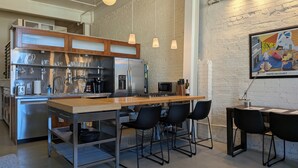 Eine moderne Küche mit Edelstahlgeräten, einer Holzanbar und schwarzen Stühlen.