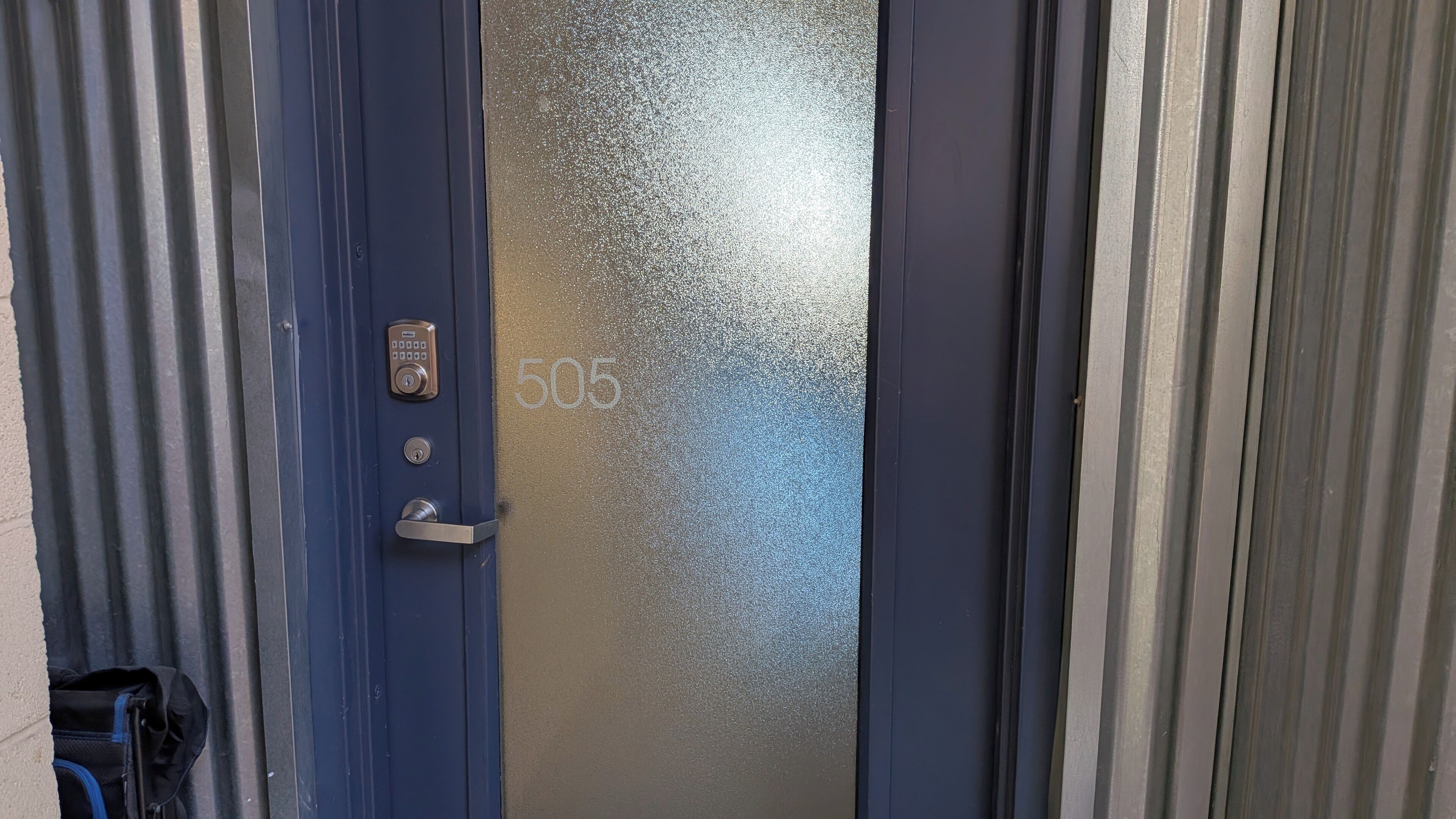 A blue door with a numeric keypad lock and a door number 505.