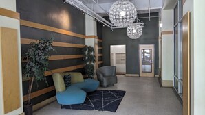 Ein moderner Empfangsbereich mit einem blauen Sofa, einem grauen Sessel und einem Blumentopf.