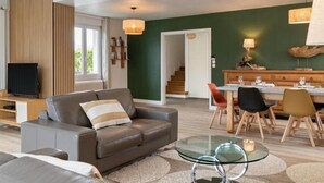 Una sala moderna con un sofá de cuero, una mesa de centro de vidrio y un comedor con muebles de madera.