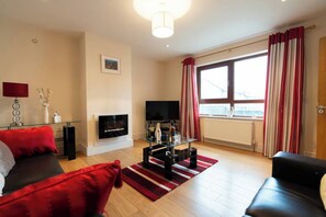 A modern living room with a fireplace, a television, and a large window with curtains.