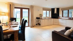 A modern kitchen with a dining area, featuring a large window, a built-in oven, and a flat-screen TV.