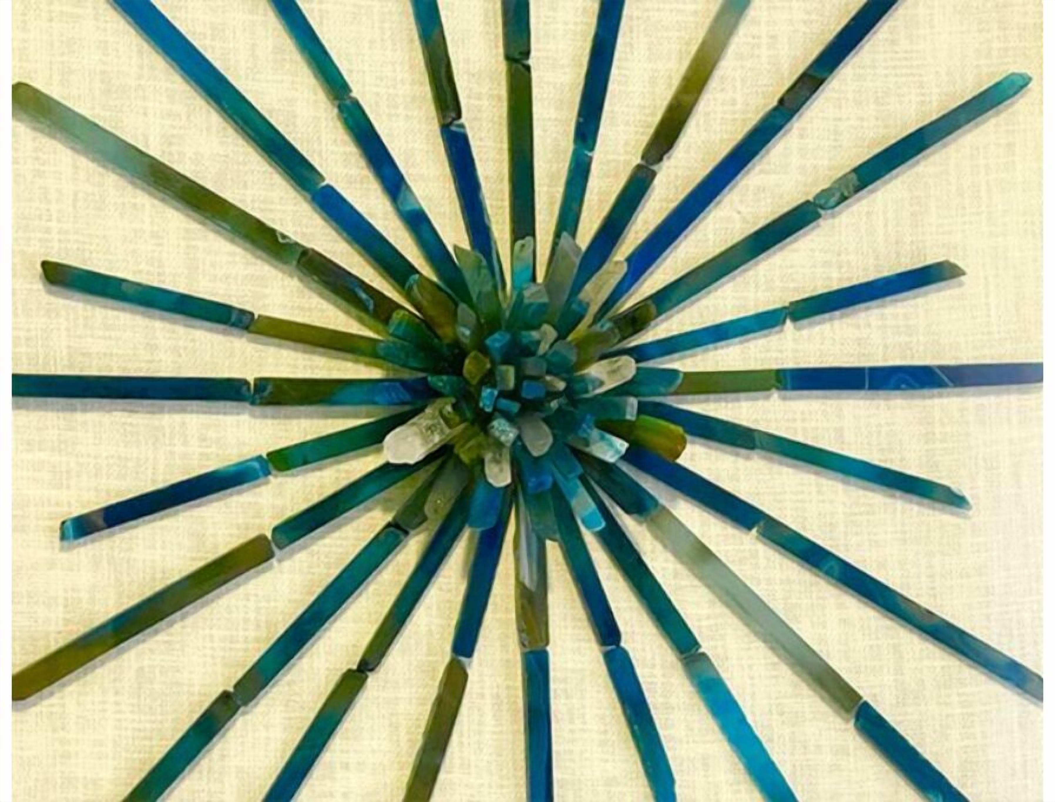 A geometric pattern of blue and green rods arranged in a radial design on a textured background.