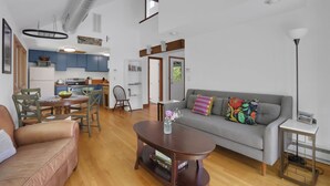 Amplia sala de estar con un sofá gris, una mesa de centro de madera y un comedor con una mesa redonda y sillas.