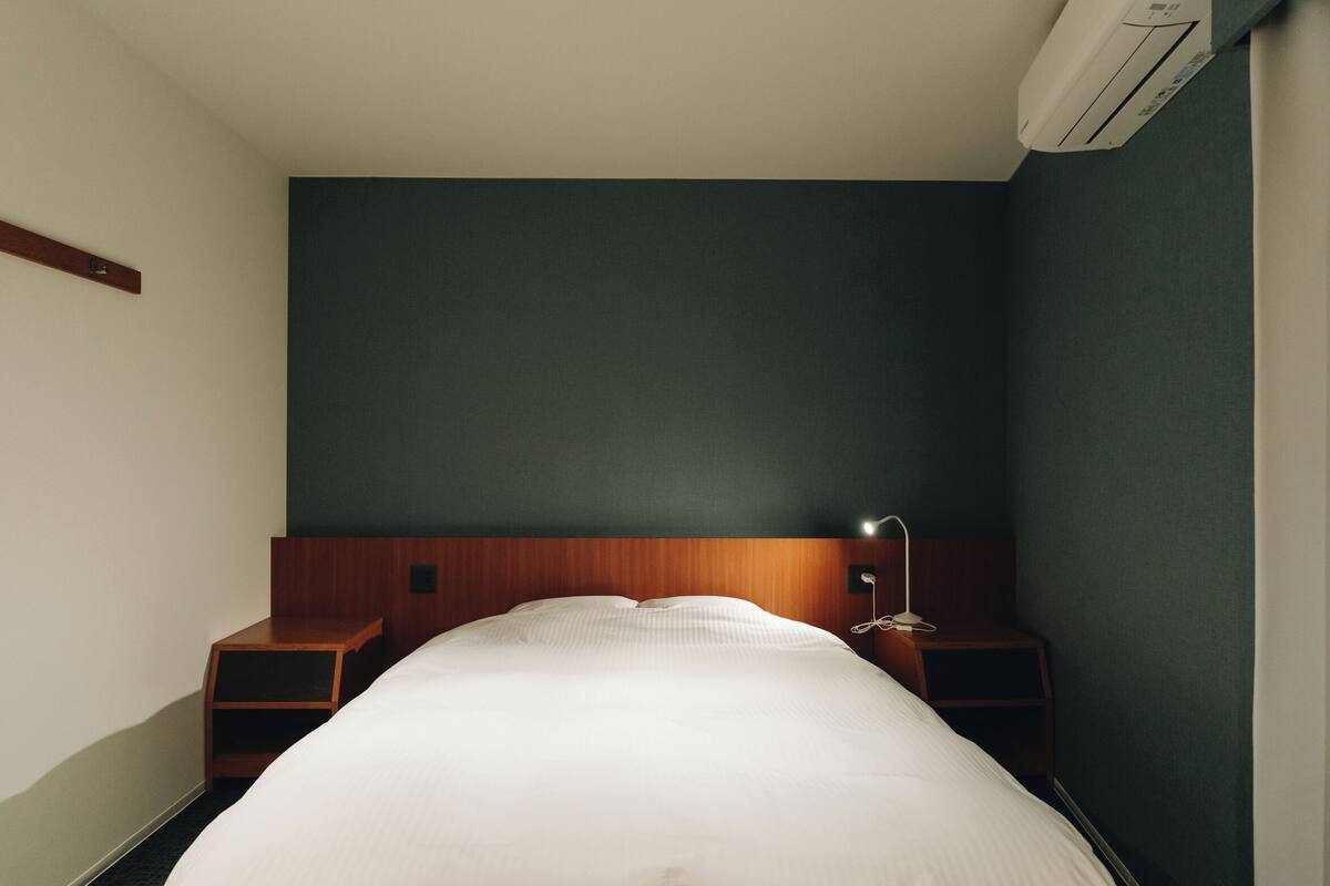 Ein Hotelzimmer mit einem großen Bett, einem Holzkopfteil, Nachttischen und einer Wand-Klimaanlage.