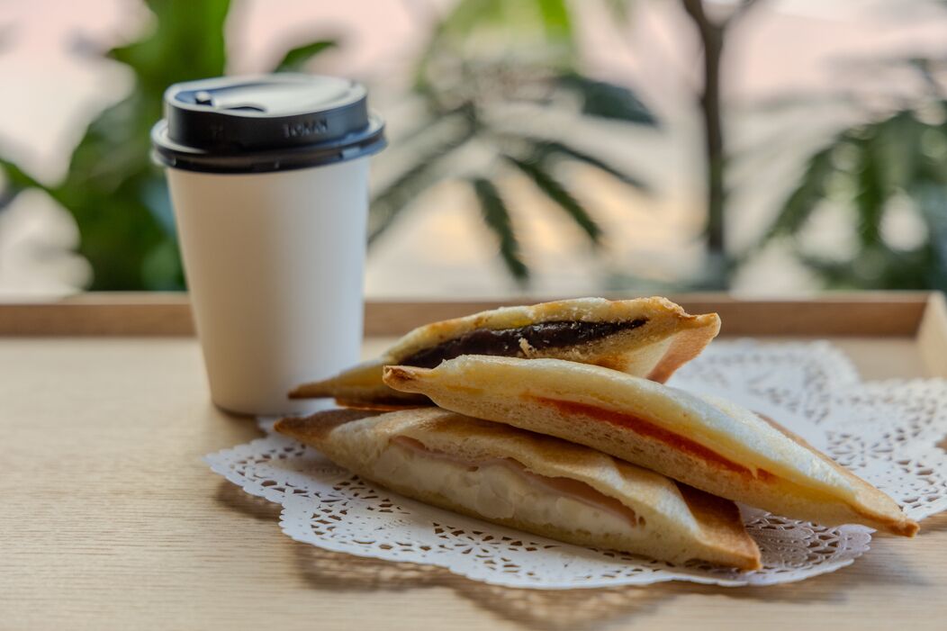 A sandwich and a disposable cup on a tray with a doily.