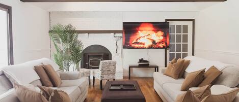 Ein modernes Wohnzimmer mit Kamin, Fernseher und zwei Sofas.