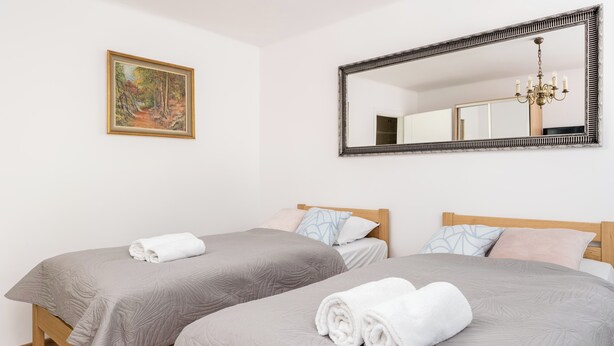 Ein Hotelzimmer mit zwei Betten, einem großen Spiegel, einem Gemälde und einer Kristallleuchtre.