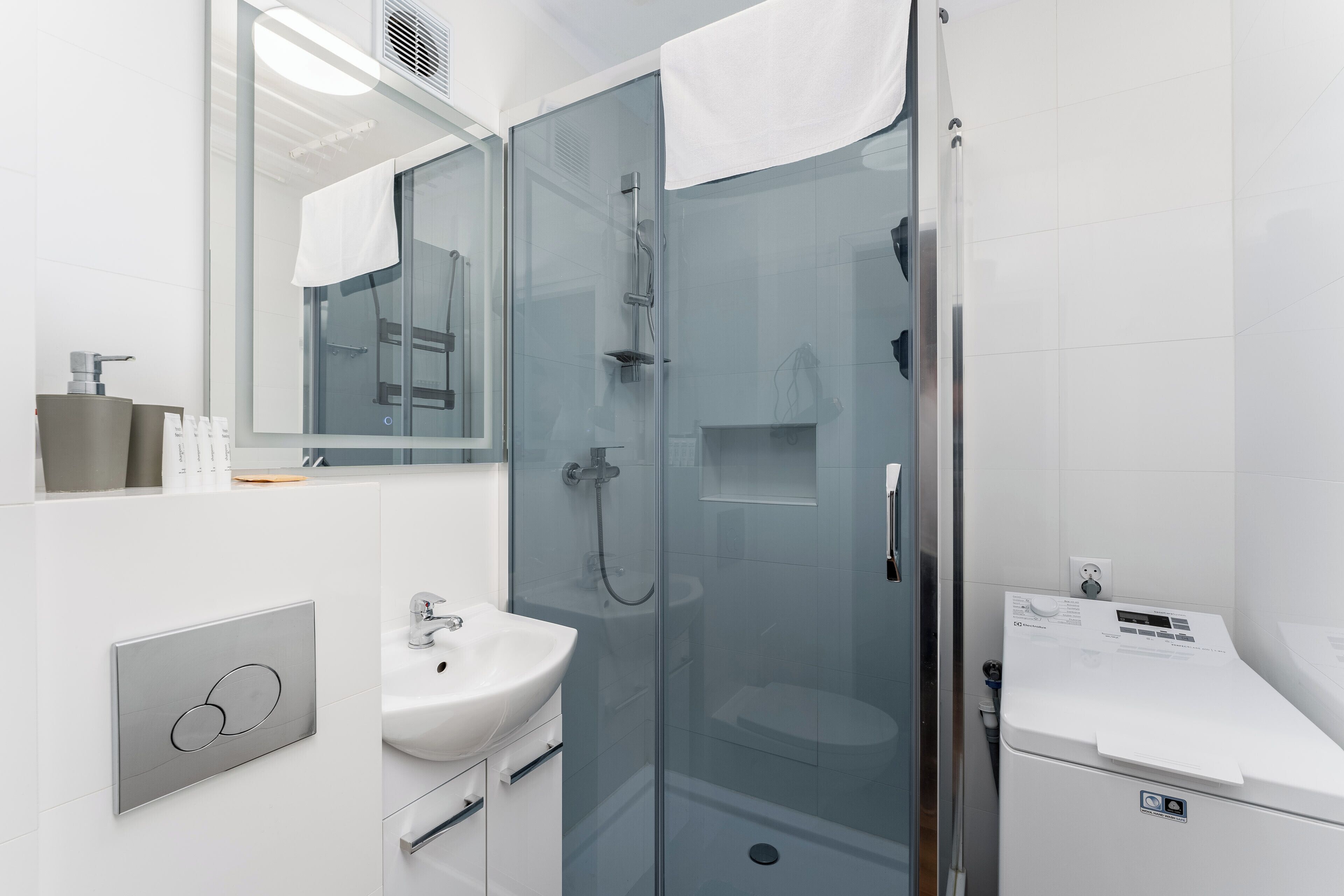 A modern bathroom with a glass-enclosed shower, a white sink, and a mirror.