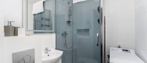 A modern bathroom with a glass-enclosed shower, a white sink, and a mirror.