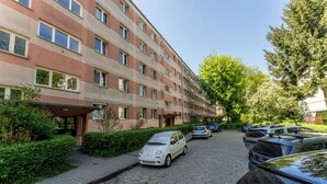Kerrostalorakennus, jossa on useita kerroksia ja pysäköintialue sen edessä.