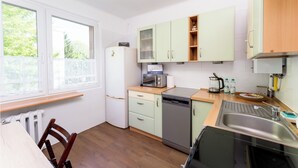 Eine kompakte Küche mit Kühlschrank, Mikrowelle und Geschirrspüler. Ein Fenster sorgt für natürliches Licht und die Arbeitsfläche ist aus Holz.