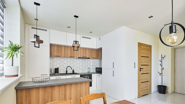 A modern kitchen with wooden cabinets, a central island, and pendant lighting. - Słowackiego Avenue Cozy Stay Studio (Kraków)