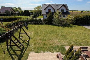 Enjoy a serene outdoor space with a lawn and a wooden swing set, surrounded by lush vegetation.