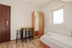 Cozy retreat with a single bed, wooden wardrobe, and small table with stools.