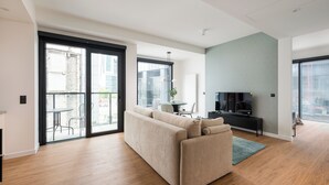 A modern living room with a sofa, a TV, and a dining area with chairs and a table.