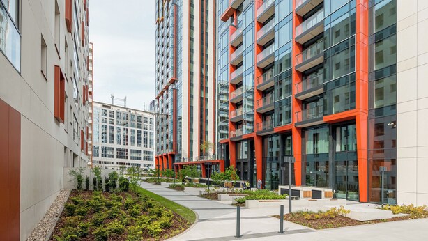 A modern apartment building with multiple balconies, a landscaped courtyard, and a pedestrian pathway.