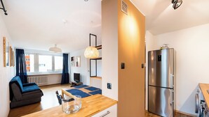 Een moderne keuken met een roestvrijstalen koelkast, een houten aanrecht en een eethoek met een tafel en stoelen.