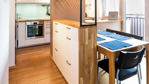 Een kleine keuken met witte kastjes, een houten aanrechtblad en een ingebouwde oven.