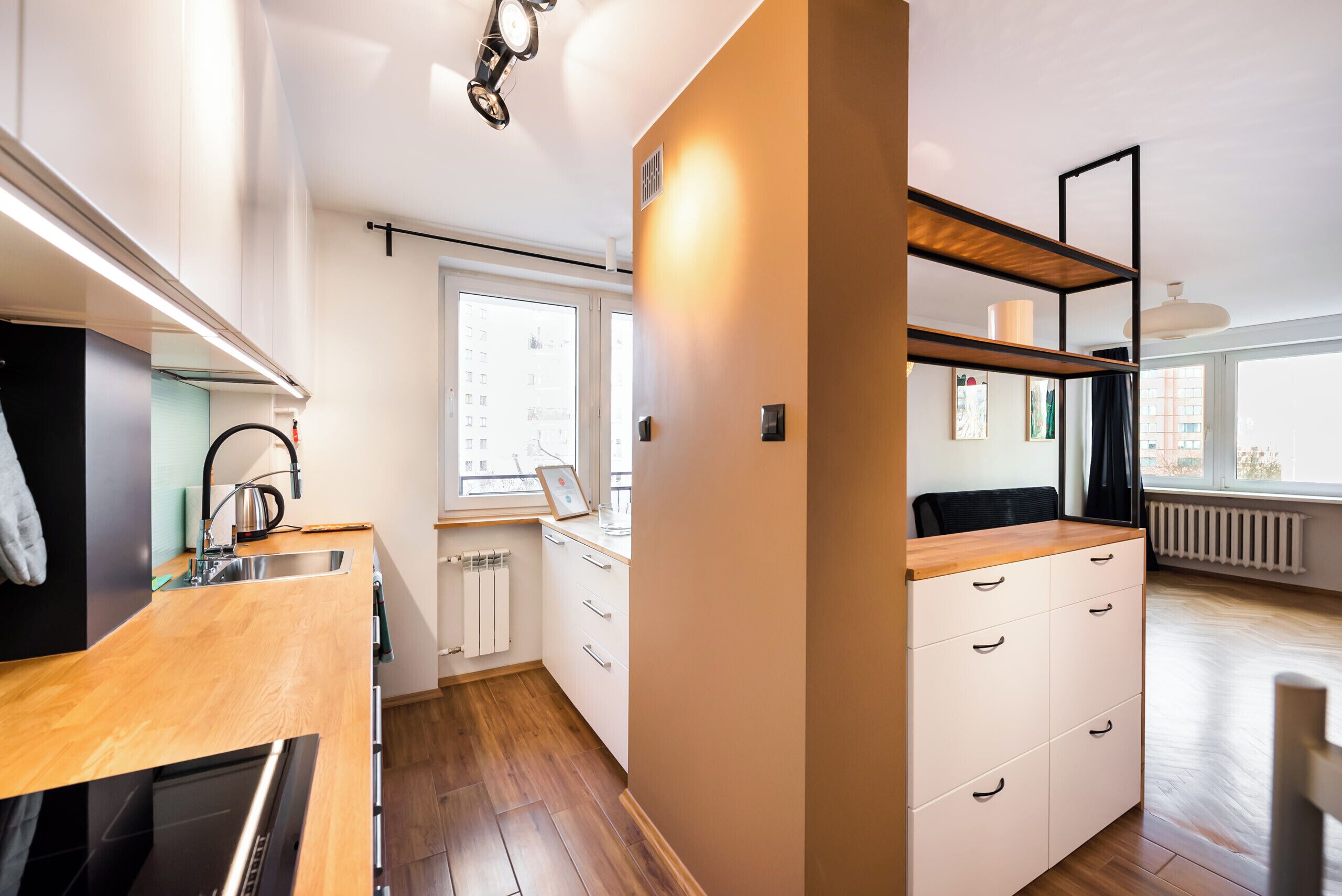 Cocina moderna con encimeras de madera, horno empotrado y ventana con vistas a la ciudad.