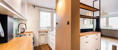Cocina moderna con encimeras de madera, horno empotrado y ventana con vistas a la ciudad.