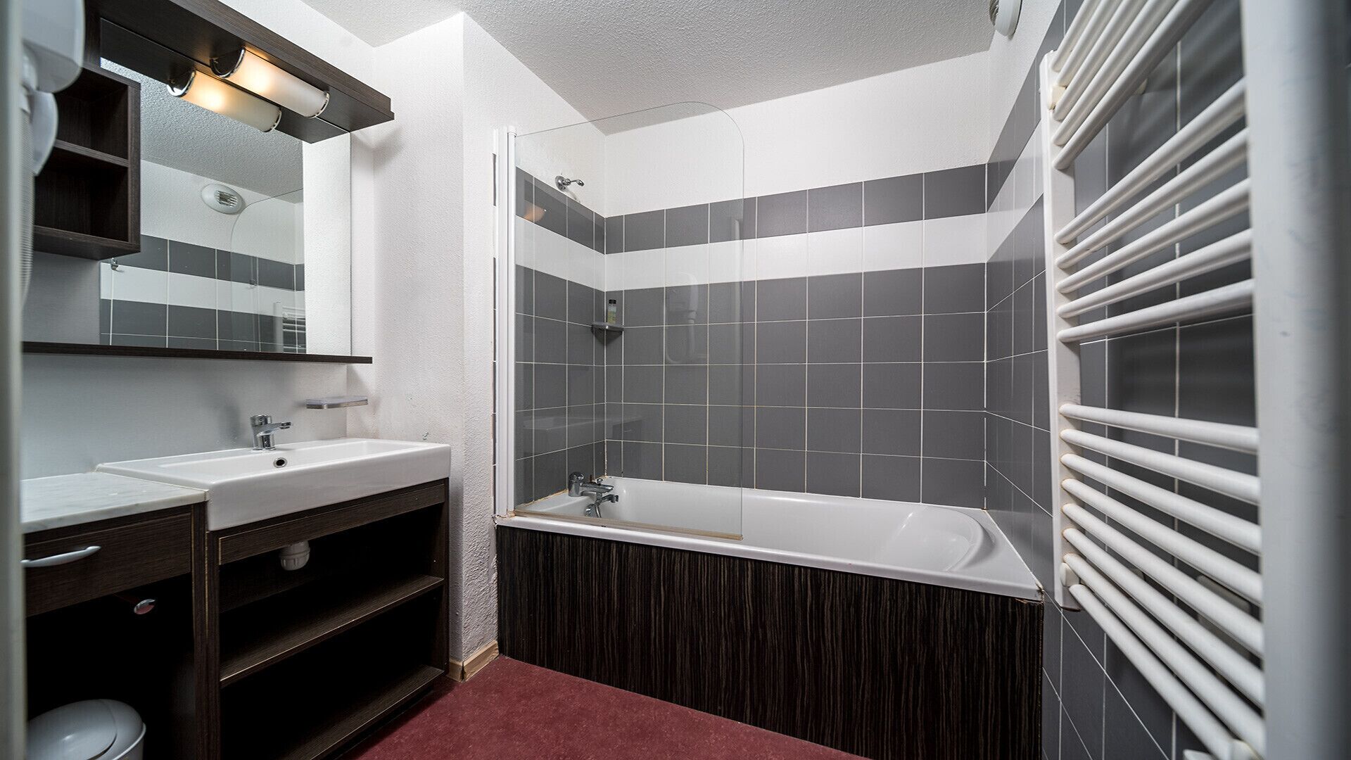 A modern bathroom with a white bathtub, a double sink vanity, and a large mirror.