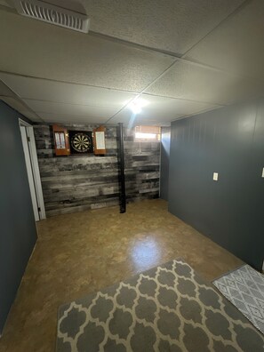Une pièce avec un mur en bois, un jeu de fléchettes et un tapis à motifs.