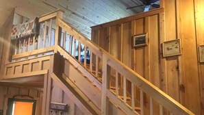 A wooden interior with a staircase, a leather couch, and a sign reading "GONE FISHIN". - Paradise on the Little Red River and prime trout fishing! (Heber Springs)