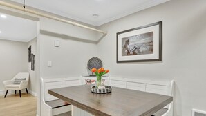 A dining area with a wooden table, white benches, a vase with flowers, and a framed picture on the wall. - Cozy and Chic 1-Bedroom Apartment in Historic Central Denver - Pet Friendly (Denver)