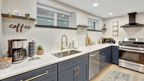A modern kitchen with a coffee station, a sink, a microwave, and an oven. - Cozy and Chic 1-Bedroom Apartment in Historic Central Denver - Pet Friendly (Denver)