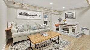 A modern living room with a sofa, coffee table, and a cityscape artwork on the wall. - Cozy and Chic 1-Bedroom Apartment in Historic Central Denver - Pet Friendly (Denver)