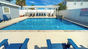Une piscine à l’eau bleue, entourée d’une clôture blanche et agrémentée d’une pergola.