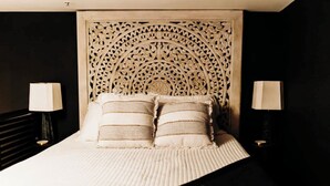 Un letto con una testiera decorativa, due abat-jour e cuscini a righe.