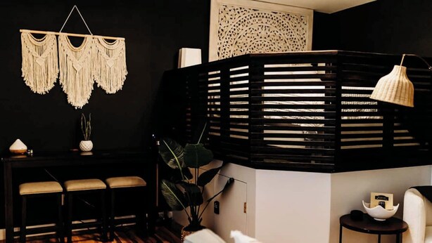 Un soggiorno moderno con un divisorio nero, un tavolo da pranzo in legno, un divano bianco e un tappeto decorato.