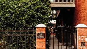 Un cancello conduce a un edificio con facciata in mattoni e un balcone.
