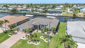 A residential area with houses, a canal, and palm trees. - Heated Pool, Gulf Access & Dock, Pet Friendly - Villa Canal Breeze - Roelens (Cape Coral)