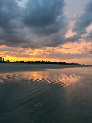 Una playa con un mar tranquilo que refleja el cielo.