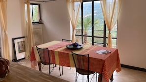 Un comedor con una mesa dispuesta para cuatro, una araña y una ventana con cortinas.