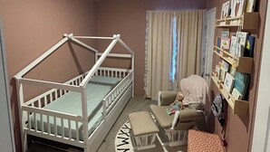 Une chambre d’enfant avec un lit superposé, un bureau, une chaise et une bibliothèque.