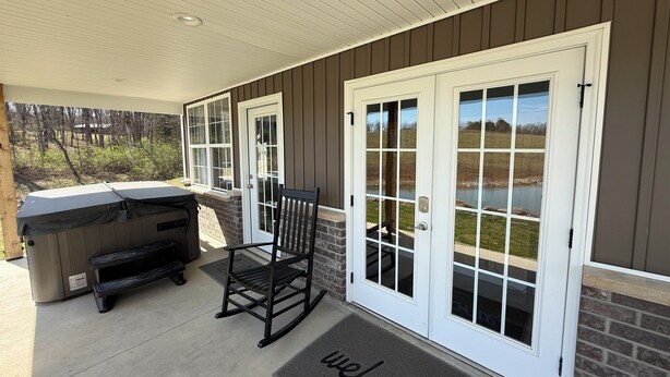 A covered patio with a grill, a rocking chair, and a welcome mat. - Private Cabin on 90 Acres! (Troy)