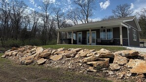 A building with a covered porch, large windows, and a stone foundation. - Private Cabin on 90 Acres! (Troy)