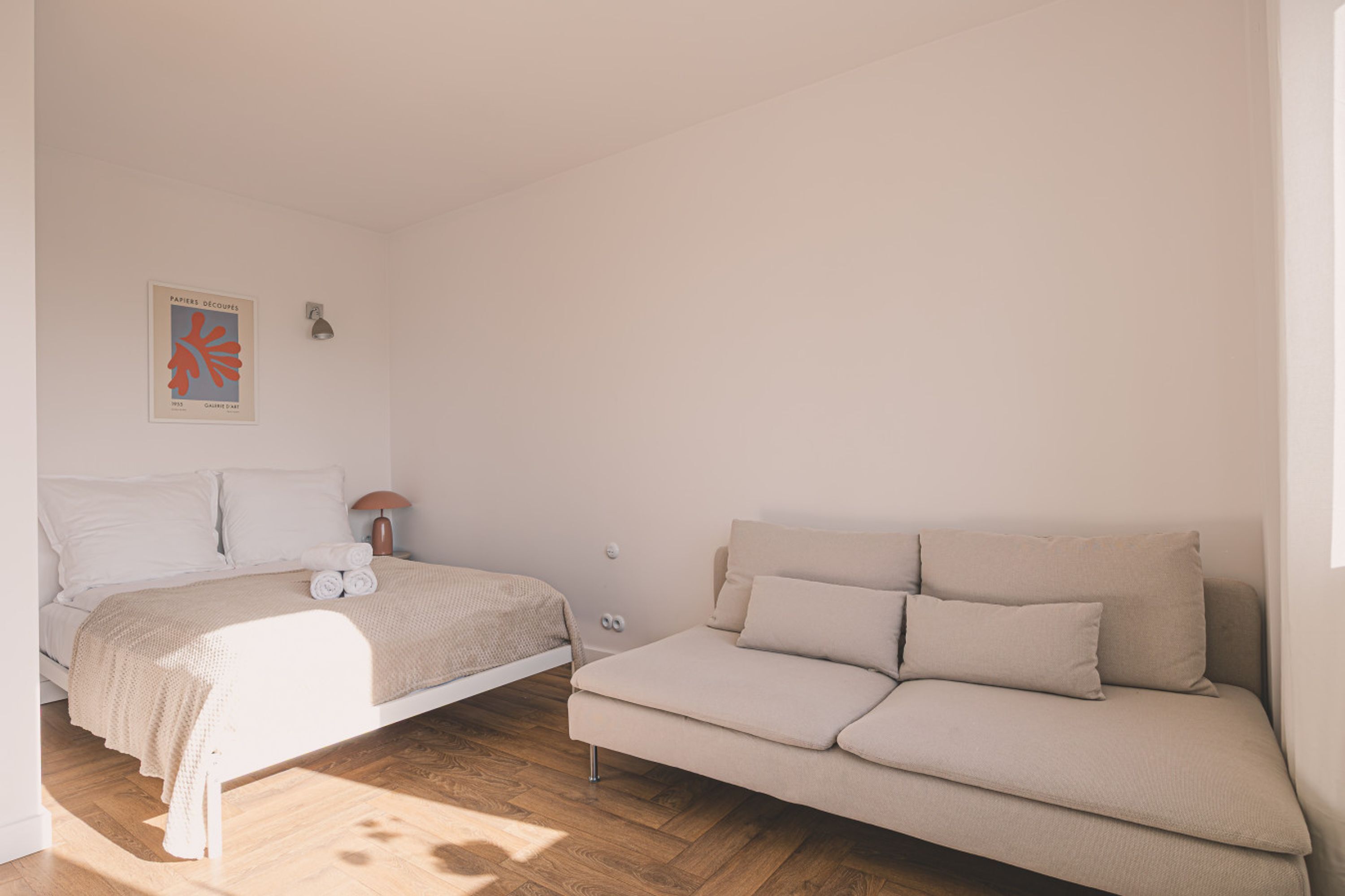 Un dormitorio con cama, sofá, lámpara y un cartel en la pared.