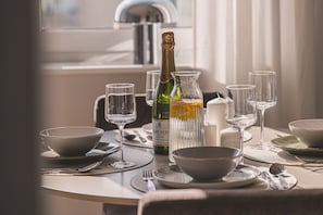 A dining table set with plates, bowls, glasses, and a bottle of champagne.