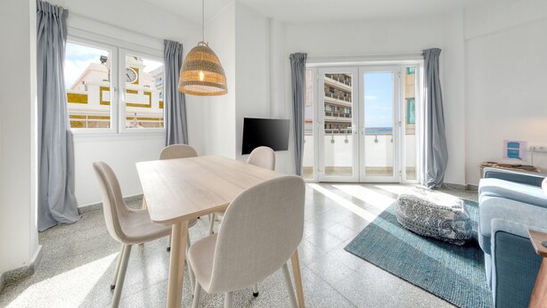 Una sala moderna con comedor, ventanas amplias y vistas a edificios.