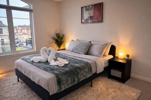 A bedroom with a bed, a bedside table with a lamp, a window with a view, and a painting on the wall. - 4BR Group Retreat by Canterra Stays · Sleeps 12 (Brampton)