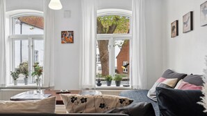 Una habitación con una cama, una mesa y dos ventanas con cortinas.