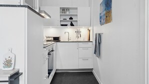 Una cocina estrecha con armarios blancos, un microondas y un lavamanos.