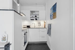 A compact kitchen with white cabinets, a microwave, and a toaster.