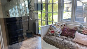 Une pièce chaleureuse avec une banquette intégrée, de grandes fenêtres, une cheminée et une vue sur l’extérieur.