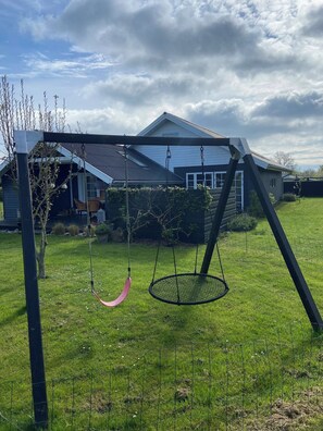 A swing set in a grassy yard with a house in the background. - Lovely holiday home near Funens beautiful nature (Otterup)